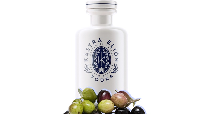 Abottle of Kastra Elion vodka on a white background with olives in the foreground