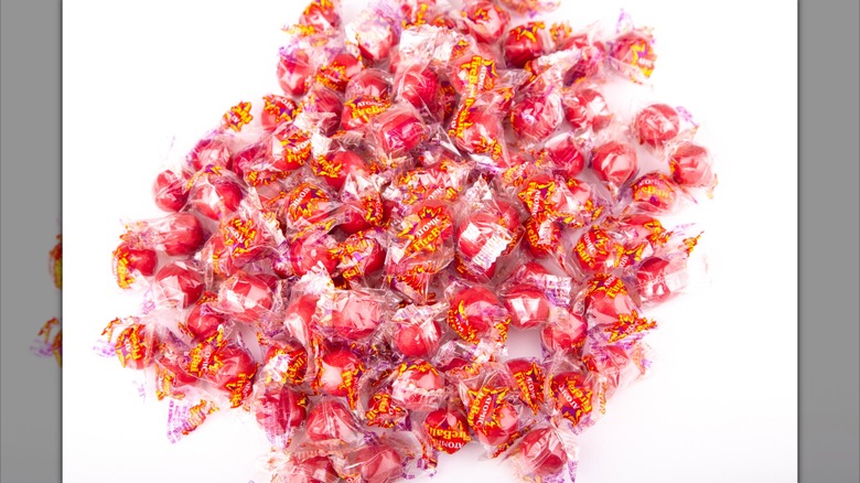 A pile of Atomic Fireballs candies in wrappers sit on white background.