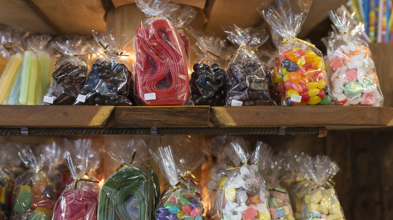 Clear bags of old-fashioned candy sit on wooden shelves, like jelly beans, taffy, and candy strips
