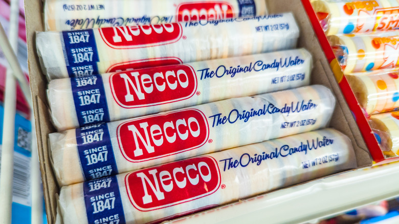 A box of rolls of Necco Wafers sit on a store shelf.