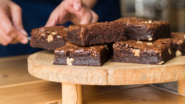hands placing brownies on wooden plate