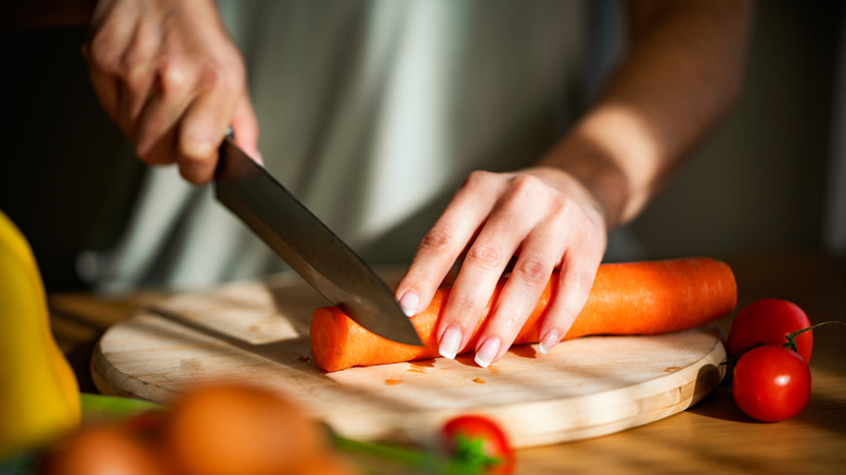 person chopping carrots on cutting board