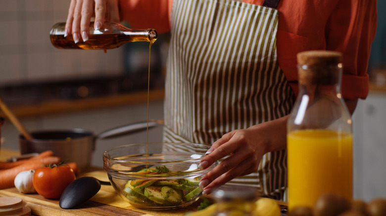Pouring oil onto vegetables in bowl