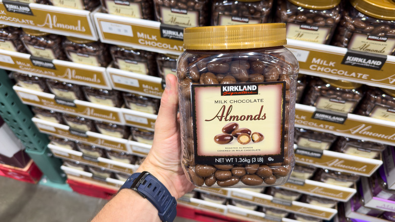 Customer holding Kirkland Signature chocolate almonds in the store by a display