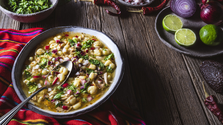 Bowl of pozole surrounded by fresh ingredients