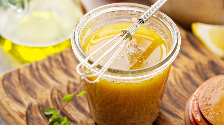 Jar of homemade salad dressing and mini whisk