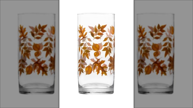 A tall drinking glass with a fall leaf design.
