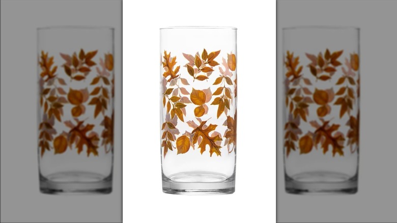 A tall drinking glass with a fall leaf design