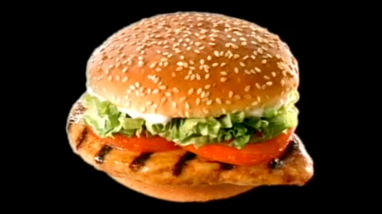 Chicken Whopper with lettuce, tomato, and mayo on a sesame seed bun, on black background.