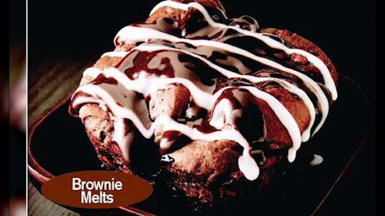 McDonald's brownie melts topped with fudge and white icing, on a black background.