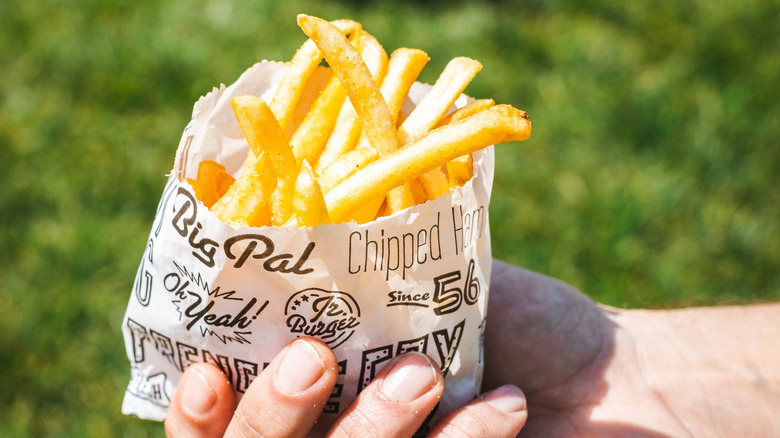 Hand holding a bag of Pal's fries