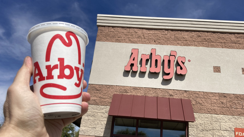 Arby's Coke cup near restaurant sign