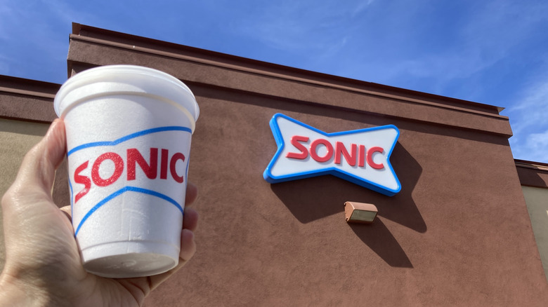 Hand holding a Sonic Coke cup outside the restaurant