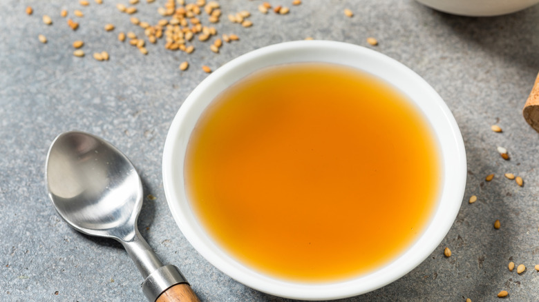 Bowl of toasted sesame oil, sesame seeds, and spoon