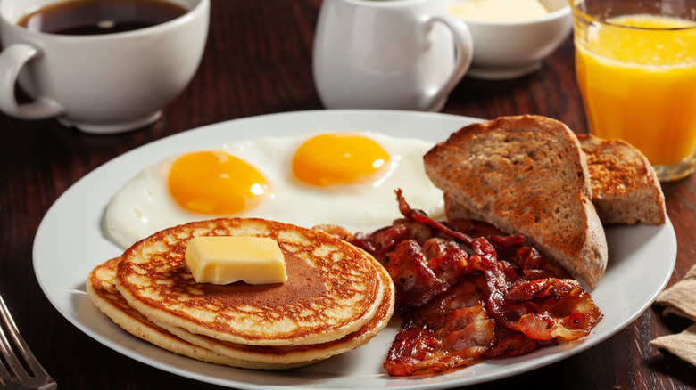 Full American breakfast with eggs, pancakes, bacon, toast, and coffee