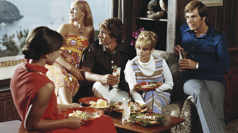 Vintage photo of a dinner party with people wearing 1970s style outfits
