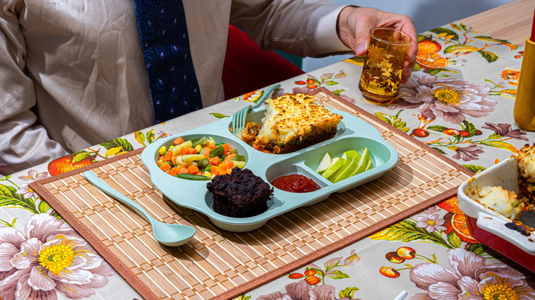 Vintage TV dinner on the table with a man holding a glass