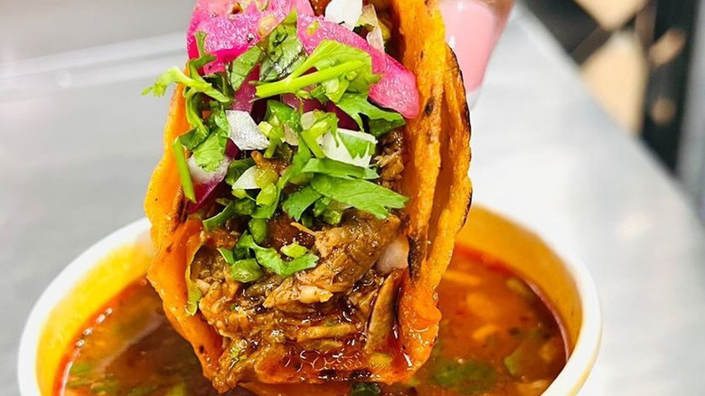 A Birria-Landia taco dipped in its signature broth