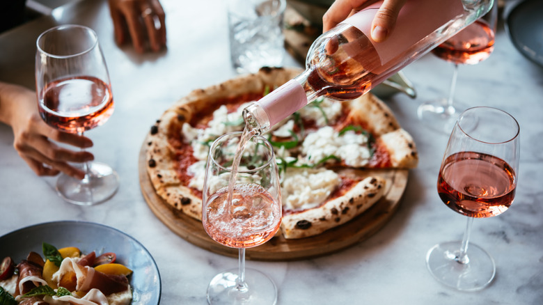Wine being poured with pizza