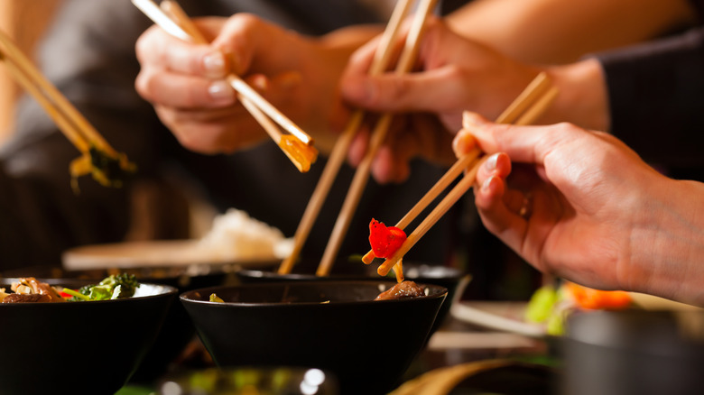 A group of people using chopsticks at a Chinese restaurant