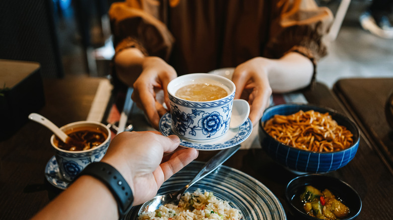 Hands passing tea across a table
