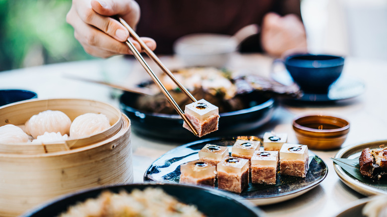 A person using chopsticks to lift piece of dim sum