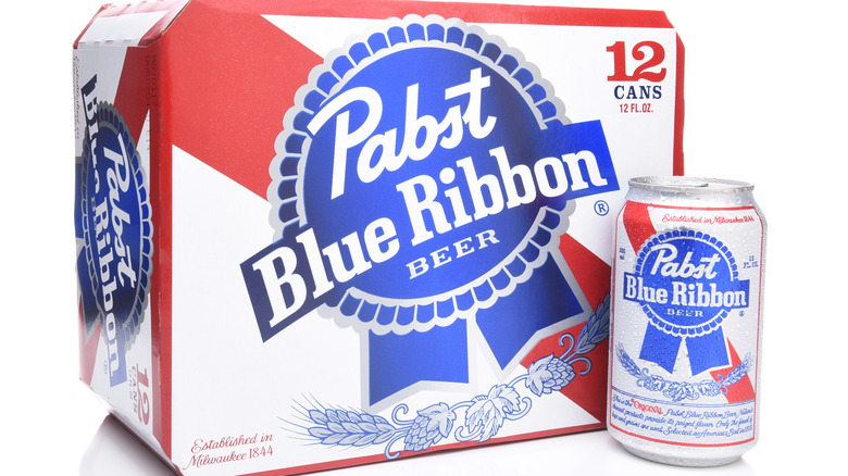 A 12-pack of Pabst Blue Ribbon next to a singular can of the same beer