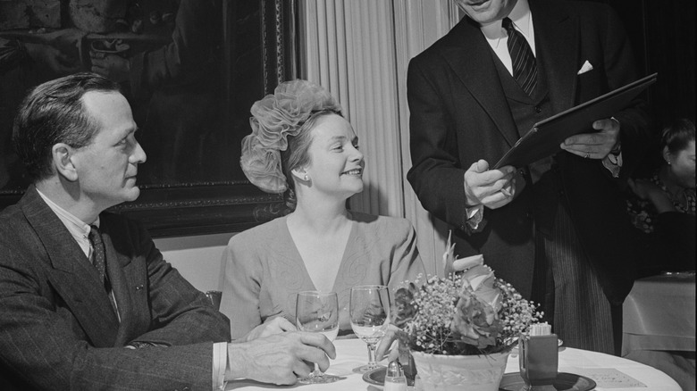 Couple in 1945 restaurant club with waiter