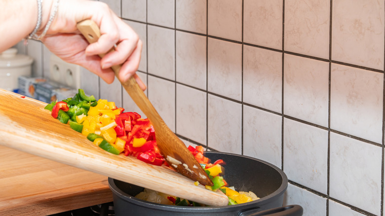 Diced veggies being added to pot on stove