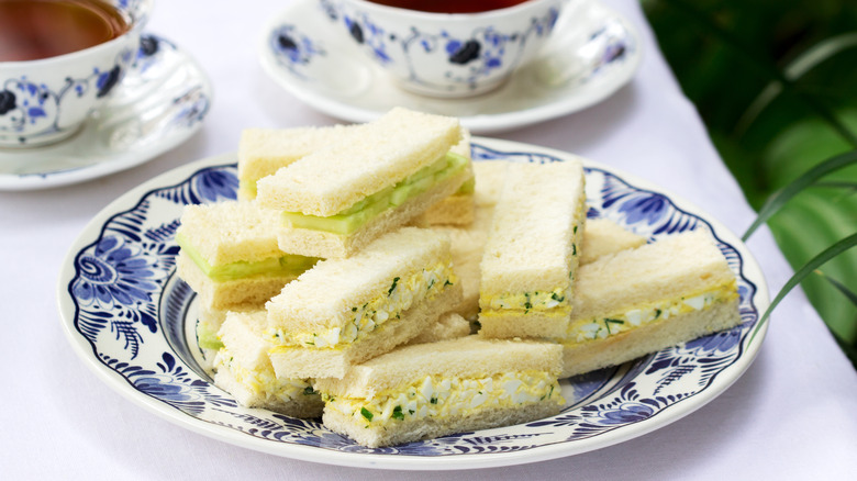 Assortment of tea sandwiches on china plate with tea