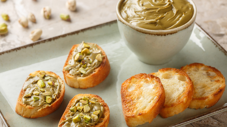 Pistachio nut butter on bread with a bowl of spread in the background