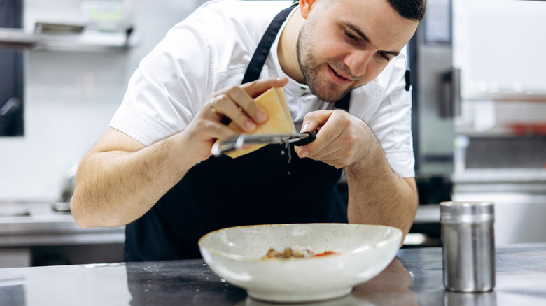Chef grating parmesan on pasta