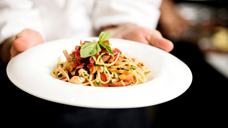 Hands holding a plate of pasta