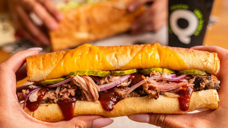 Hands holding Quiznos sub sandwich