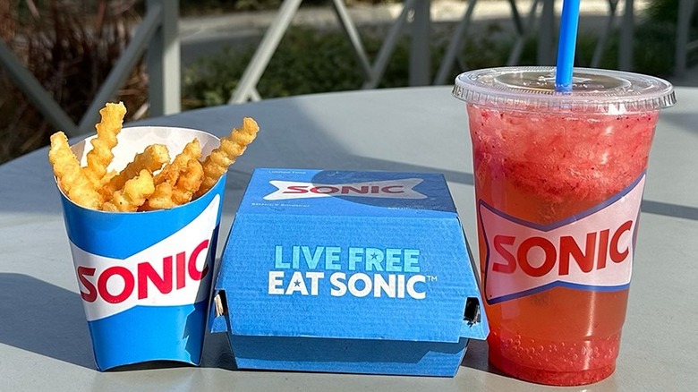 Sonic Drive-In french fries, burger, and beverage on an outdoor table