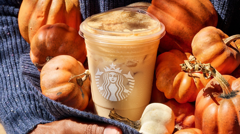 Starbucks Iced Pumpkin Spice Latte cup in armful of pumpkins