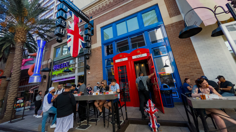 The red, white, and blue exterior of Gordon Ramsay Fish & Chips and nearby businesses