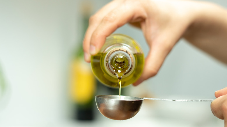 Pouring olive oil into measuring spoon