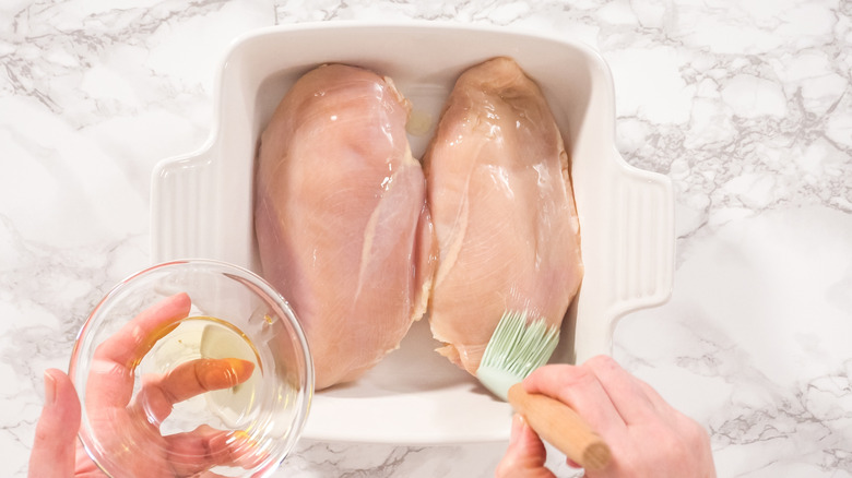 Brushing chicken breasts with oil