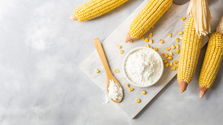 A bowl of cornstarch next to ears of corn