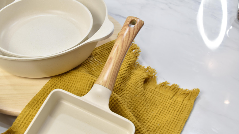 Ceramic pans and baking dishes on a golden kitchen towel
