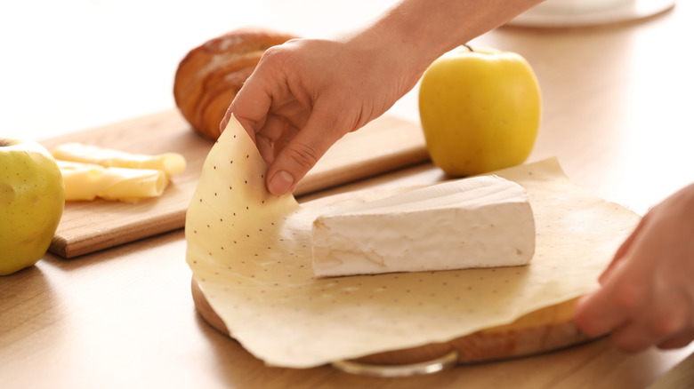 Hands wrapping cheese in paper
