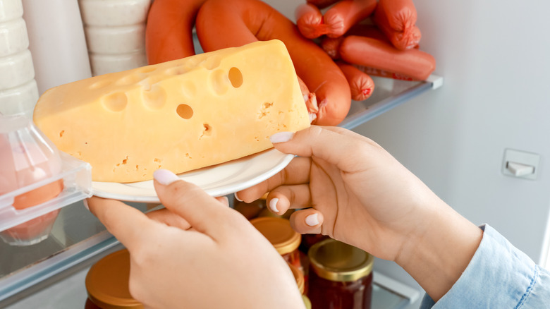Hands taking cheese out of fridge