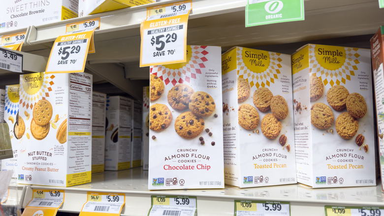 Several boxes of Simple Mills cookies on grocery store shelf, including Crunchy Chocolate Chip Cookies