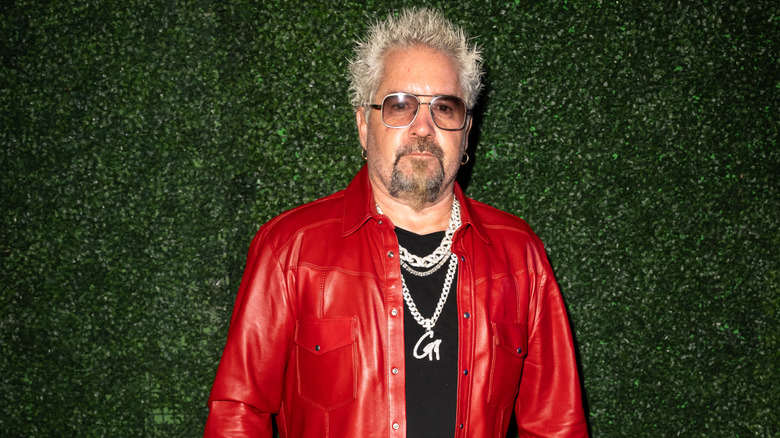 Close-up of Guy Fieri with a neutral green foliage background