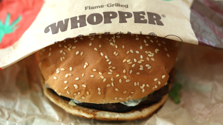 A half-unwrapped Burger King Whopper showing the sesame buns and patty.