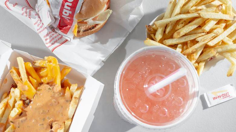 A top-view photo of In-N-Out burger Signature Pink Lemonade, a burger, plain fries, and Animal Style Fries
