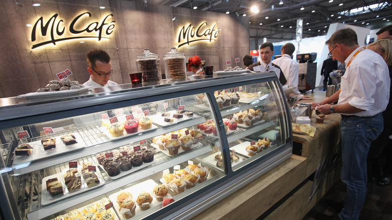 McDonald's McCafe display case and counter with customers paying for their orders