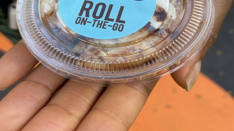 A closeup of a Cinnabon Roll On The Go bun in a clear, plastic container