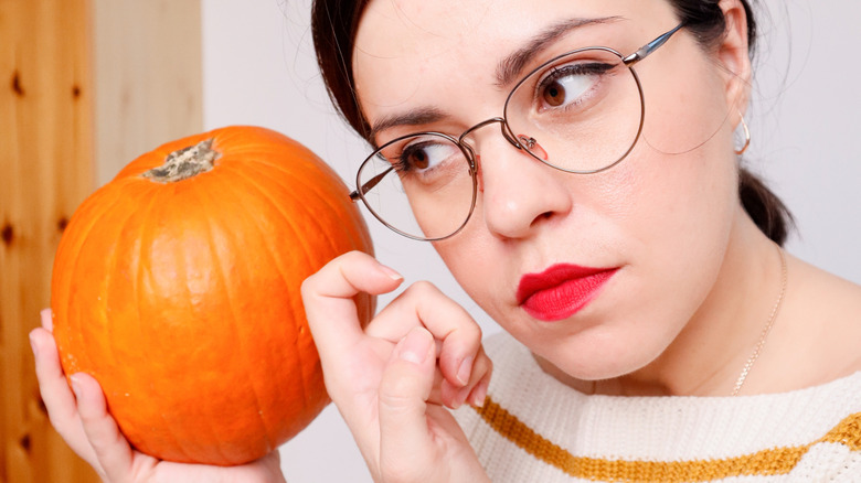 woman tapping on side of pumpkin